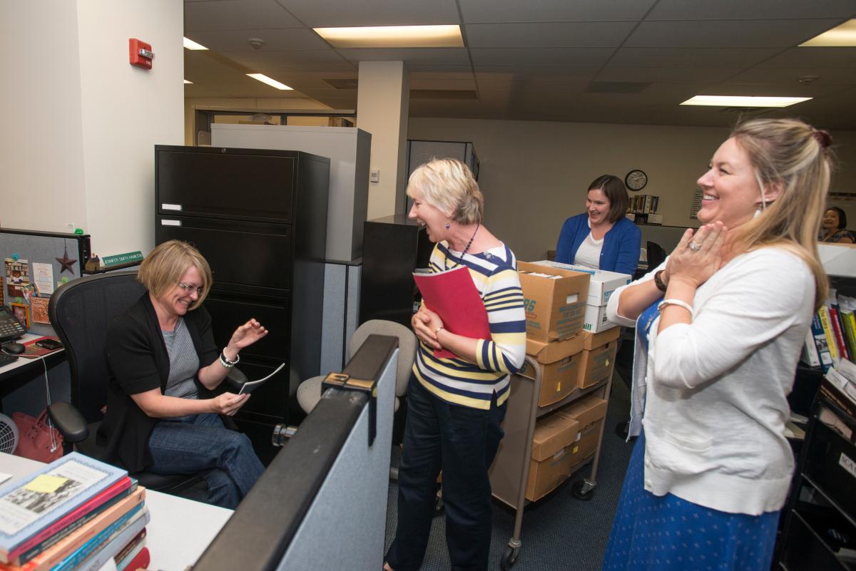 Library workers smiling at each other in a cubicle